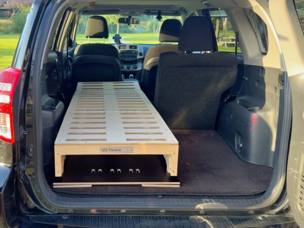 A Trunk Mate Sleeping Platform neatly installed in an SUV, showing sturdy wooden slats stretching from the folded back seats all the way to the rear hatch—an easy upgrade for comfy car camping adventures.