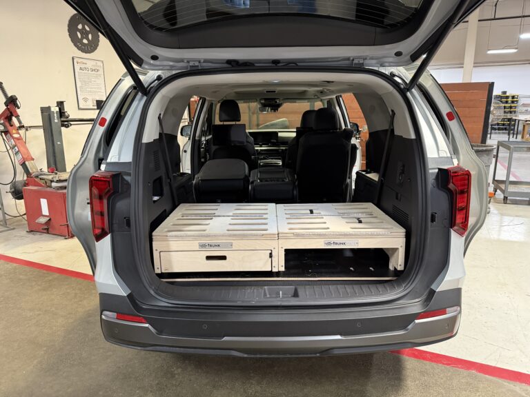 Trunk Mate Sleeping platform stacked neatly in a vehicle’s cargo area with the rear hatch open and back seats folded down, ready for adventure or extra storage right in your garage.