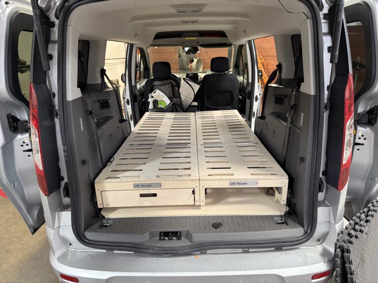 Rear view of a van with back doors open, showcasing a Trunk Mate wooden slat bed platform—perfect for maximizing storage and easily converting your van for sleeping or adventure.