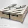 Trunk Mate wooden slotted folding platform viewed from the back, showing easy-carry cut-out handles, sturdy metal hinges, and black straps holding it together—practical design for van and SUV camping.