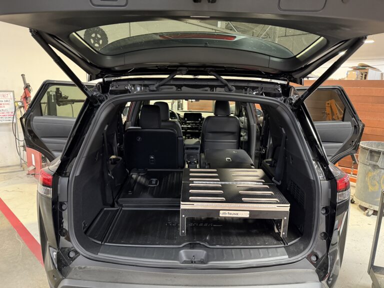Trunk of an SUV showing off a Trunk Mate Sleeping Platform securely installed in the cargo area, with the rear seats partially folded for extra storage and sleeping space.