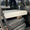 Trunk Mate Sleeping Platform set up in a car—mattress resting on a sturdy wooden base in the back seat area, front seat reclined and car door open for easy access.
