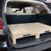 SUV rear with hatch open, featuring a TrunkMate wooden storage sleeping platform neatly installed in the cargo area, ready for adventure.