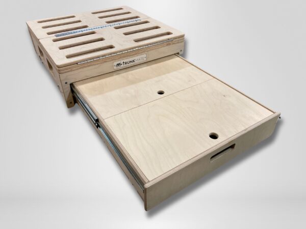 Trunk Mate Sleeping Platform shown with its signature slotted top, easy-grab cutout handles, and a smoothly sliding drawer for organized storage—all crafted from light, durable wood.