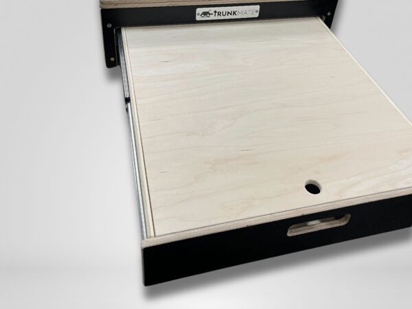 A Trunk Mate sliding wooden drawer with a handy pull handle and circular cutout, partially pulled out from a sleek black frame featuring the Trunk Mate logo—perfect for organized, on-the-go storage in your adventure rig.