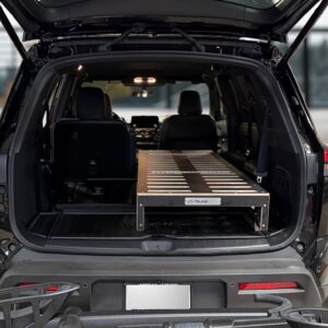 A spacious 2025 Nissan Pathfinder with its rear hatch open reveals a custom Trunk Mate Sleeping Platform—a sturdy mix of metal and wood—securely fitted in the cargo area, optimizing storage space and creating a flat sleeping surface for your next adventure.