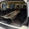 A sleek black and silver Trunk Mate sleeping platform set up in an SUV, showing off its modular design with the rear seats folded flat for plenty of sleeping space.