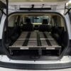 The back of an SUV with the hatch open, featuring a Trunk Mate sleeping platform stretched from the folded seats to the cargo space—ready for comfortable car camping and easy storage underneath.