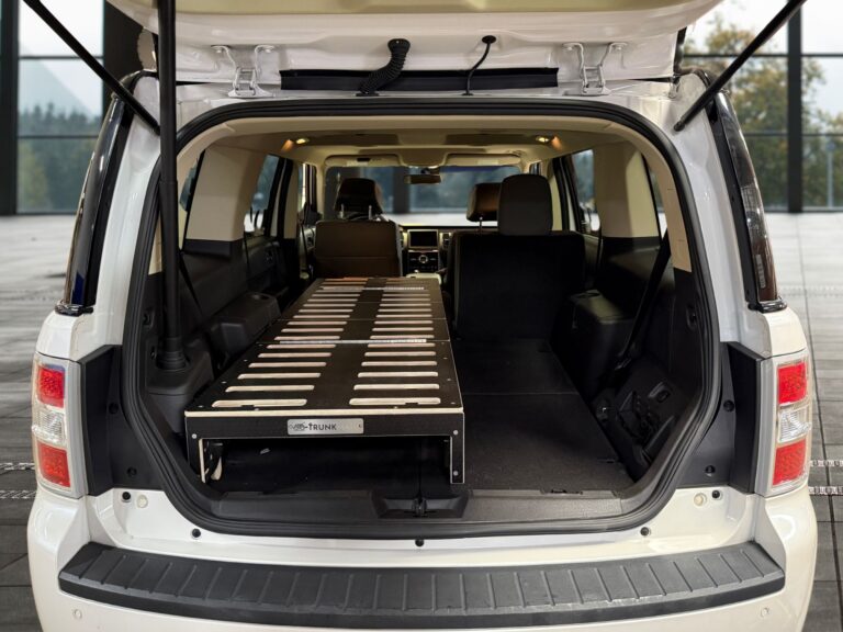 Rear view of an SUV with the tailgate open, featuring a Trunk Mate foldable black sleeping platform set up in the cargo space—perfectly prepped for camping or on-the-go adventures.