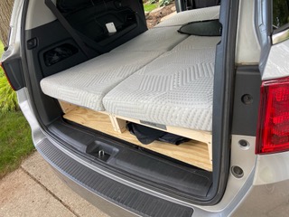 Cozy Trunk Mate Sleeping Platform set up in an SUV, featuring a comfortable mattress on top and plenty of organized wooden storage space underneath for all your gear.