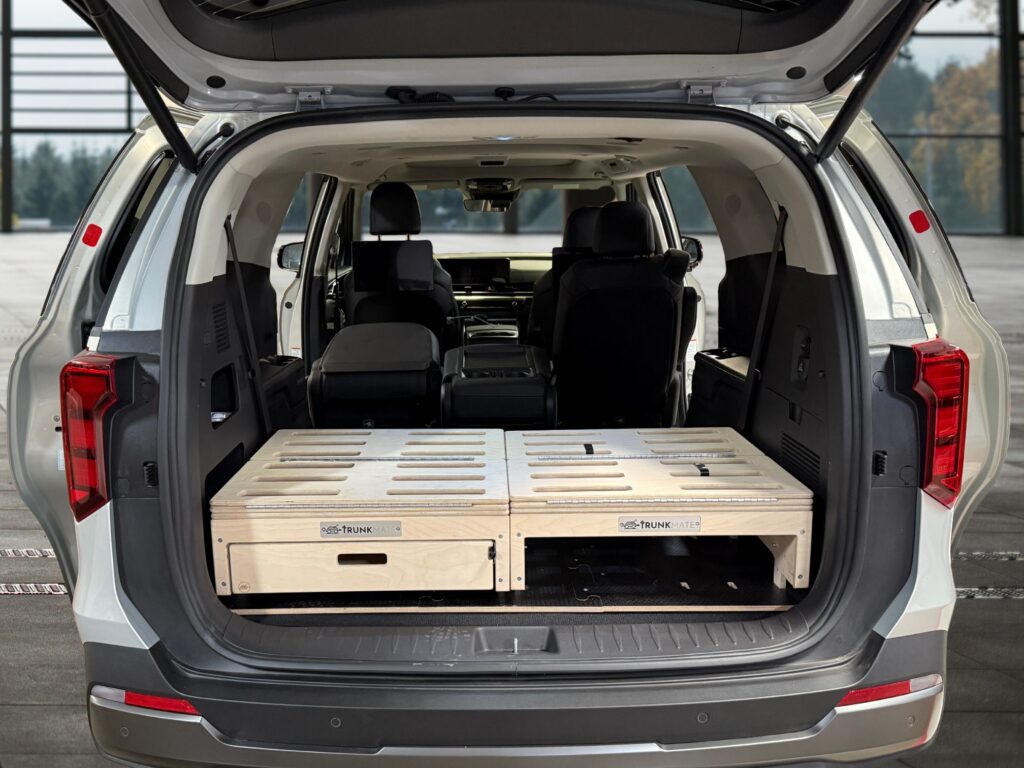 The open trunk of an SUV showing off a Trunk Mate Sleeping Platform—sleek wooden cargo storage with roomy pull-out drawers and clever compartments ready for adventure.