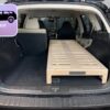 The trunk of an SUV with the rear seats folded down, showing off a Trunk Mate sleeping platform—sleek wooden slats creating a flat surface for organized storage or comfortable car camping.